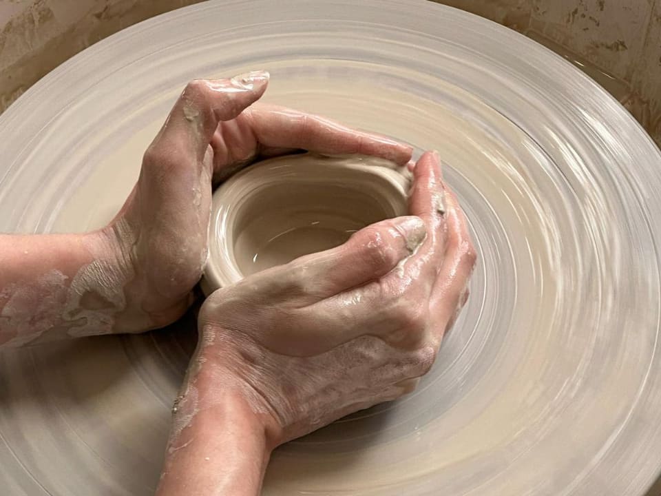 A potter centring clay on the wheel